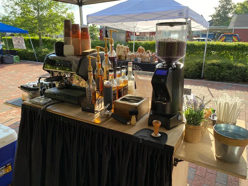 Espresso machine, grinder, and syrups set up on the cart at an outdoor festival