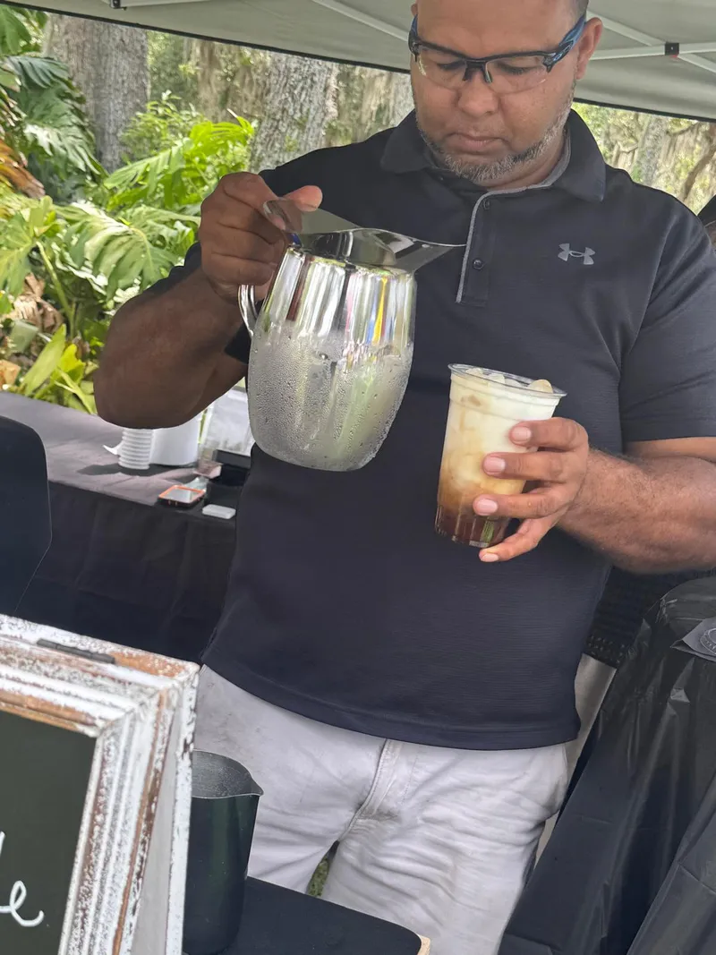 Pouring milk into an iced coffee at an outdoor event