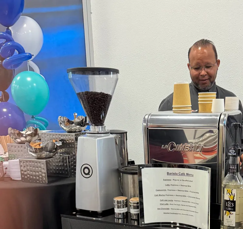 Barista behind the espresso machine at a party decorated with balloons